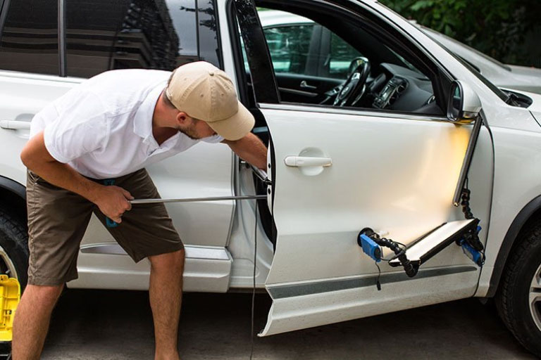 A Man Performing Paintless Dent Repair with PDR Tools