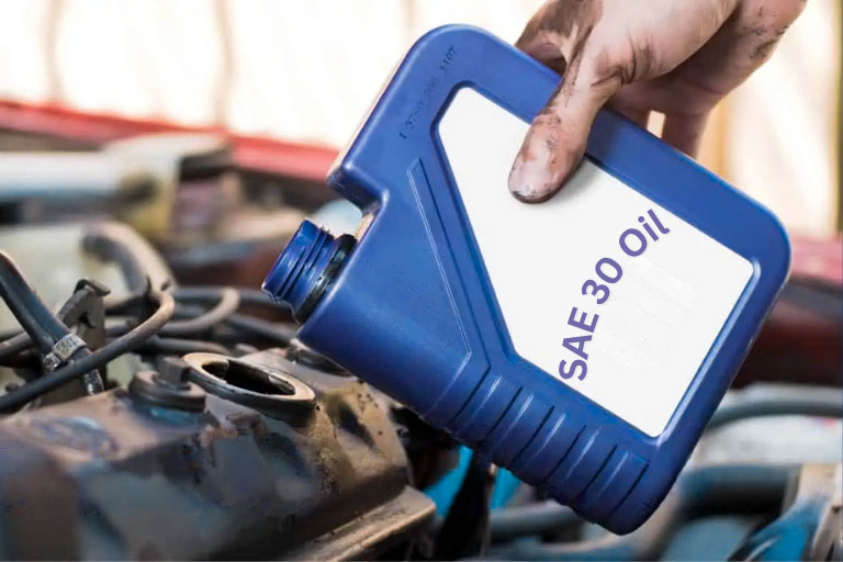 A Mechanic Pouring SAE 30 Oil in a Car Engine
