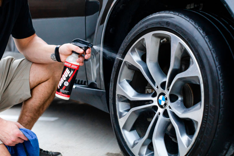 Man Spraying Polish on a Car Rim for a Shiny Finish