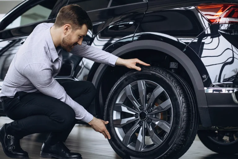 A Man Checking the Rims and Wheels of a Car
