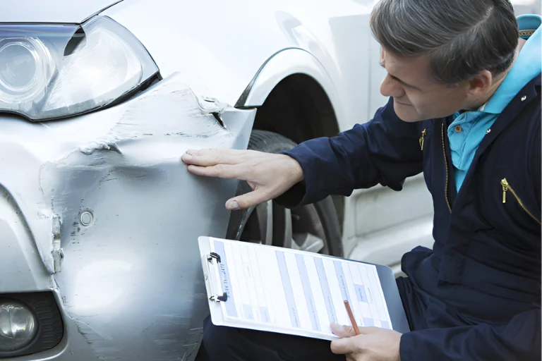 Dent vs Scratch: What Needs Immediate Repair and What Can Wait 2 A Technician Examining a Dented Car Panel