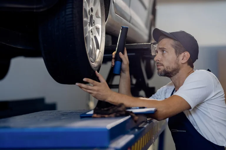 A Mechanic Checking Tire Condition and Suspension of Fleet Vehicle